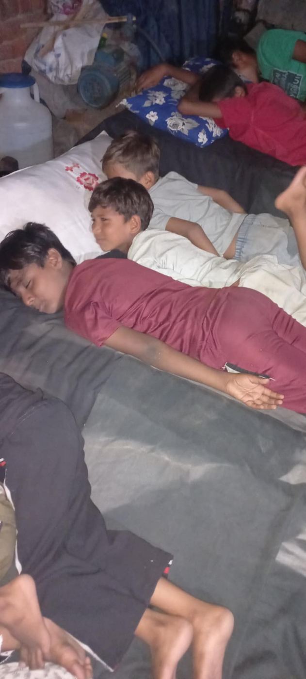 Boys sleeping crowded together on mattresses